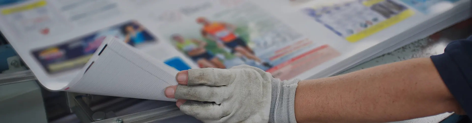 Gloved hand lifting press sheets to examine for quality control